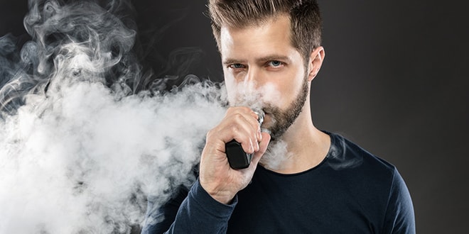 Image of a man holding a vape device with a large vapour cloud